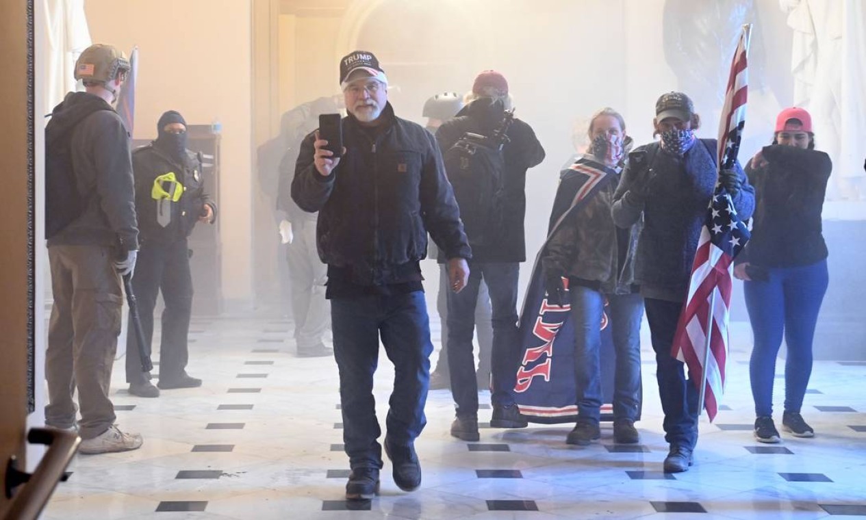Apoiadores do presidente Donald Trump no Capitólio enquanto gás lacrimogêneo lançado pela polícia toma o corredor do prédio — Foto: SAUL LOEB / AFP