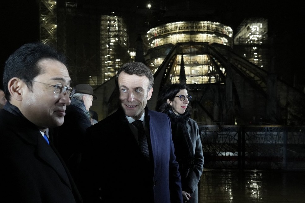 O presidente francês Emmanuel Macron ao lado da ministra da Cultura da França, Rima Abdul-Malak (dir.), visita o primeiro-ministro japonês Fumio Kishida (esq.) diante da Catedral de Notre-Dame — Foto: Thibault Camus / POOL / AFP