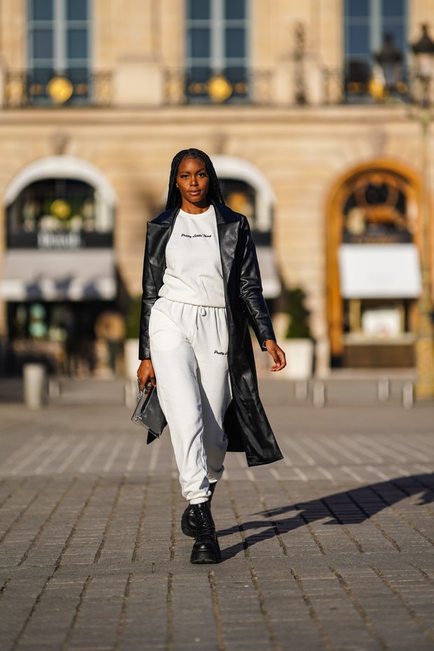 PARIS, FRANCE - FEBRUARY 27: Magalie Kab wears a black leather long coat, a white pullover from Pretty Little Things, white jogger sportswear pants, black leather boots, a silver bag contained in a clear plastic bag, on February 27, 2021 in Paris, France. (Foto: Getty Images)