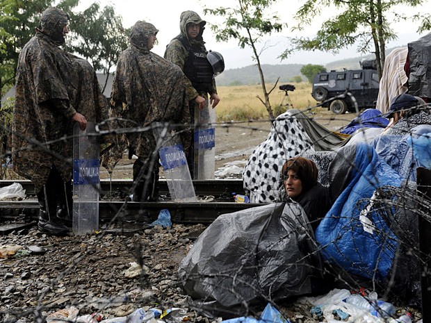 Polícia da Macedônia dica de guarda diante de imigrantes perto da passagem de fronteira com a Grécia (Foto: Alexandros Avramidis / Reuters)