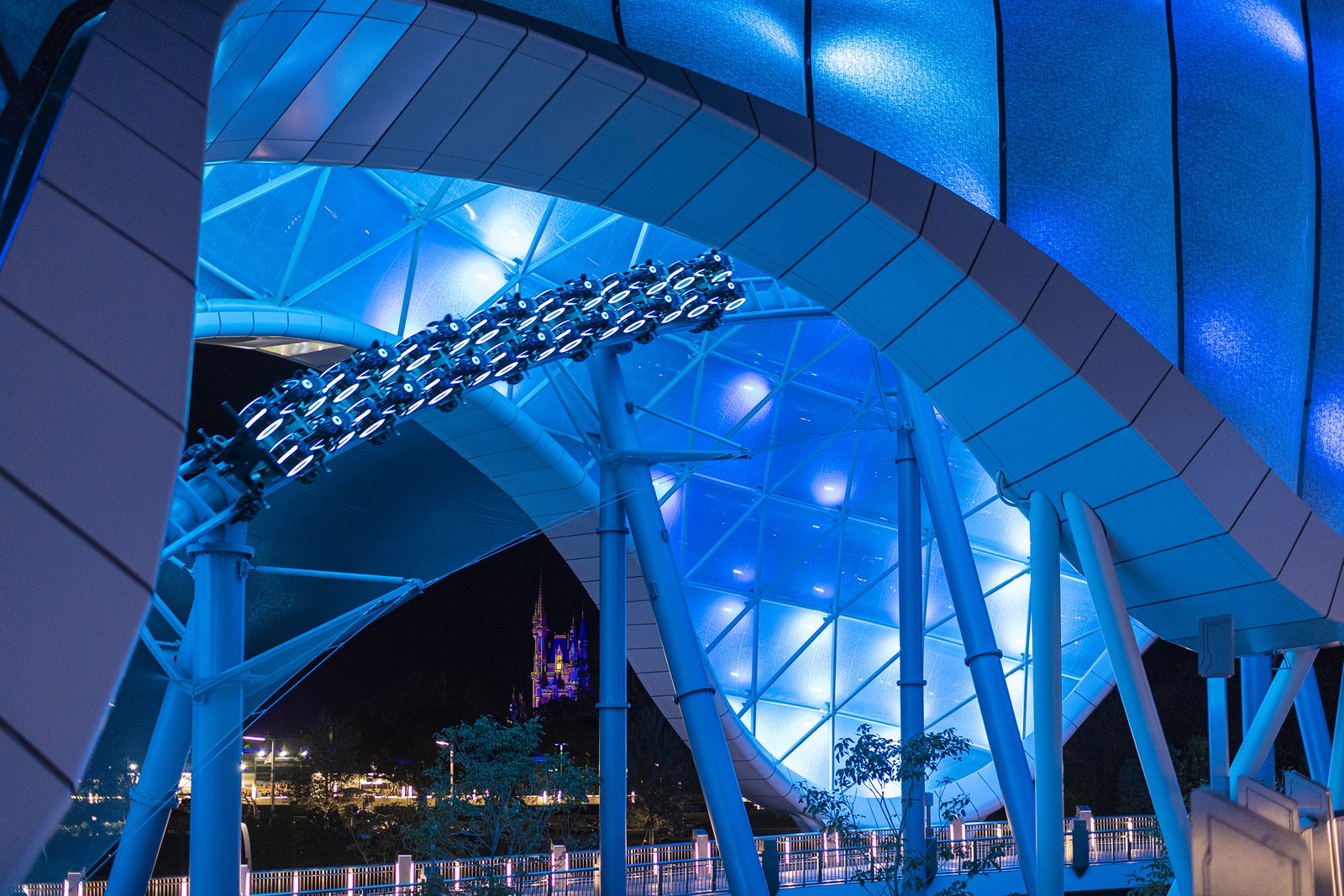 O trecho inicial do trilho da nova montanha-russa Tron Lightcycle / Run percorre uma área aberta, coberta por uma estrutura que recebe iluminação especial à noite — Foto: Divulgação / Disney Parks
