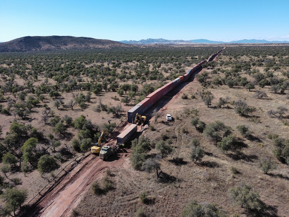 Trabalhadores removem contêineres instalados para formar um muro na fronteira do estado americano do Arizona com o México. — Foto: Robyn Beck/AFP