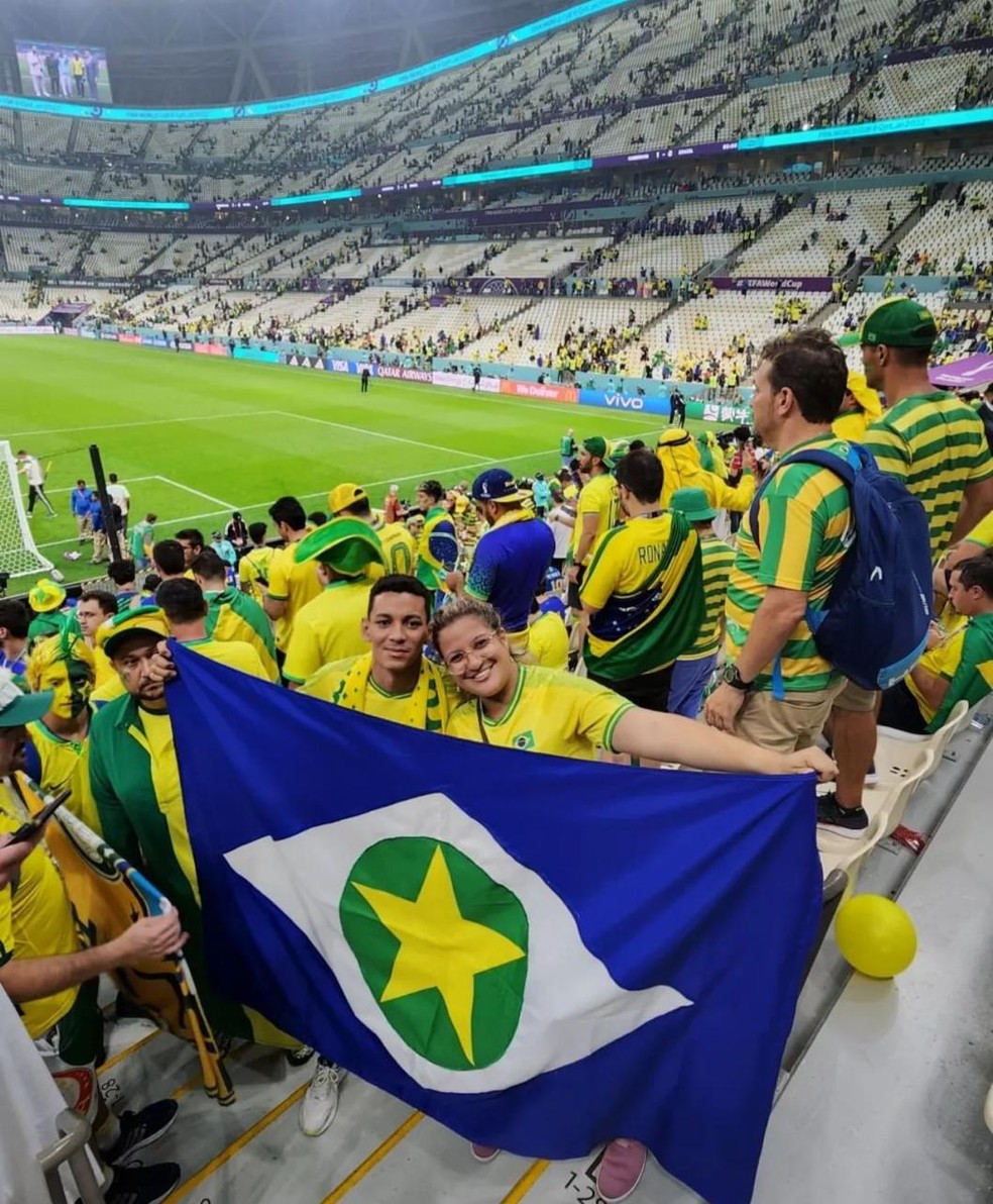 O casal levou a bandeira de Mato Grosso para um dos jogos da Copa. — Foto: Arquivo pessoal