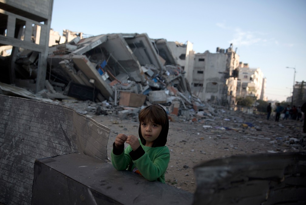 13 de novembro â CrianÃ§a palestina Ã© vista ao lado do prÃ©dio da estaÃ§Ã£o de TV Al-Aqsa, do Hamas, destruÃ­do apÃ³s ataque israelense na Cidade de Gaza â Foto: Khalil Hamra/AP