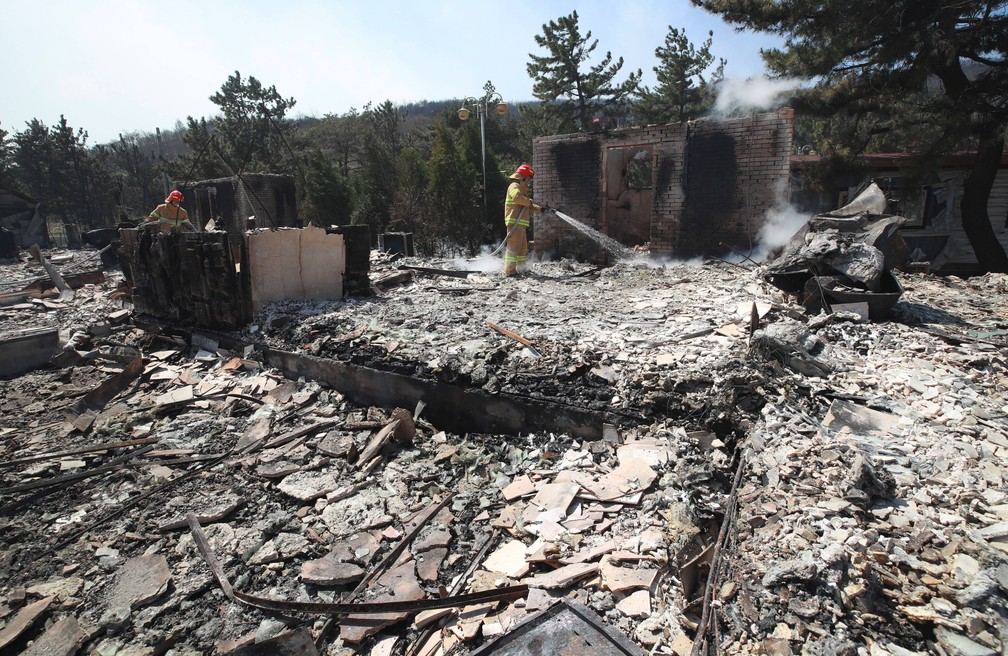 Bombeiros apagam resquícios de fogo em Donghae, área da Coreia do Sul atingida por incêndio florestal nesta quinta-feira (4) — Foto: Yonhap/AFP
