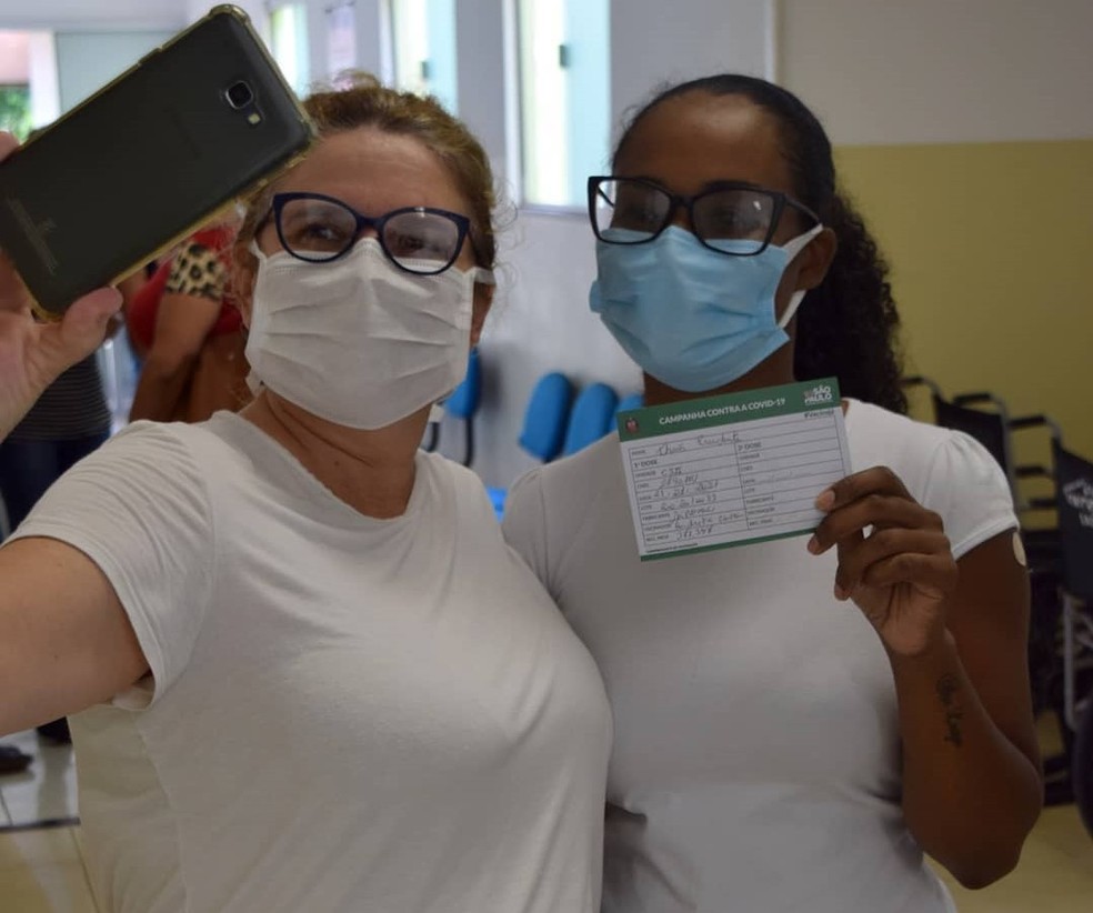 A enfermeira Thais Prudente de Abreu segura sua caderneta após ser a primeira pessoa a ser vacinada em Cafelândia — Foto: Prefeitura de Cafelândia/Divulgação