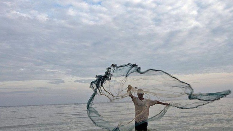 Pescador jogando rede no mar — Foto: Agência Brasil