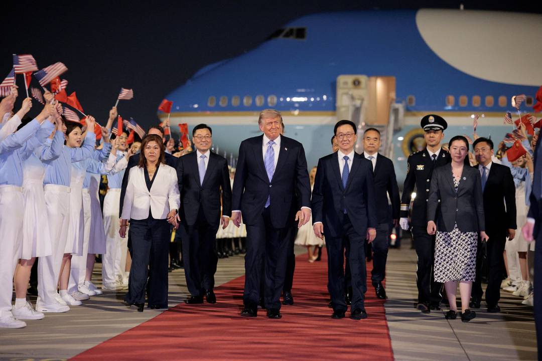 Jovens acenam bandeiras dos Estados Unidos e da China no desembarque do presidente dos EUA, Donald Trump, em Pequim, na China, em 13 de maio de 2026.