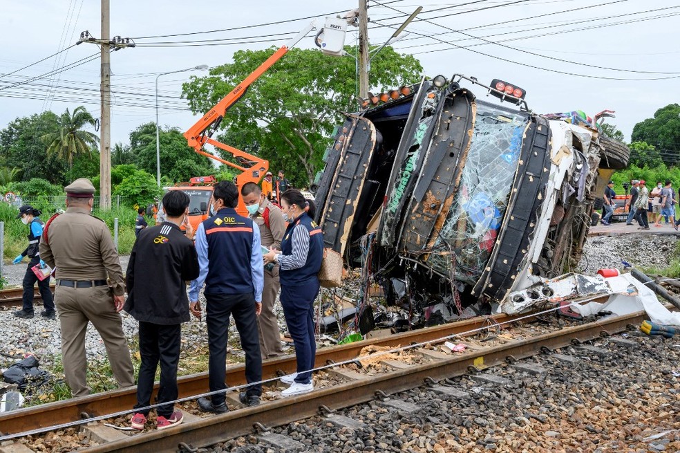 11 de outubro - Os investigadores trabalham com os destroços de um ônibus que capotou após ser atingido por um trem perto da estação ferroviária Khlong Kwaeng Klan, na província de Chachoengsao, a leste da capital tailandesa, Bangkok. — Foto: Mladen Antonov / AFP