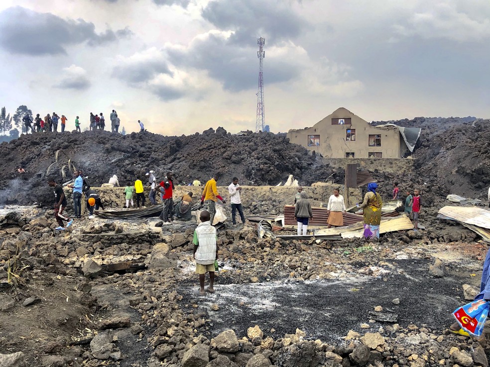 Pessoas em meio a lava fria após a erupção noturna do vulcão no Monte Nyiragongo em Goma, na República Democrática do Congo. — Foto: Clarice Butsapu/AP