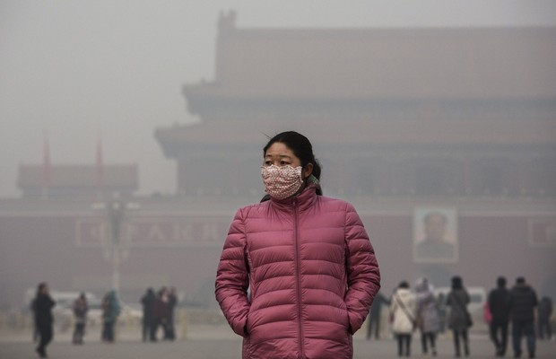 Mulher chinesa usa máscara para se proteger durante visita à praça Tiananmen em dia de alerta de poluição em Pequim, na China (Foto: Kevin Frayer/Getty Images)