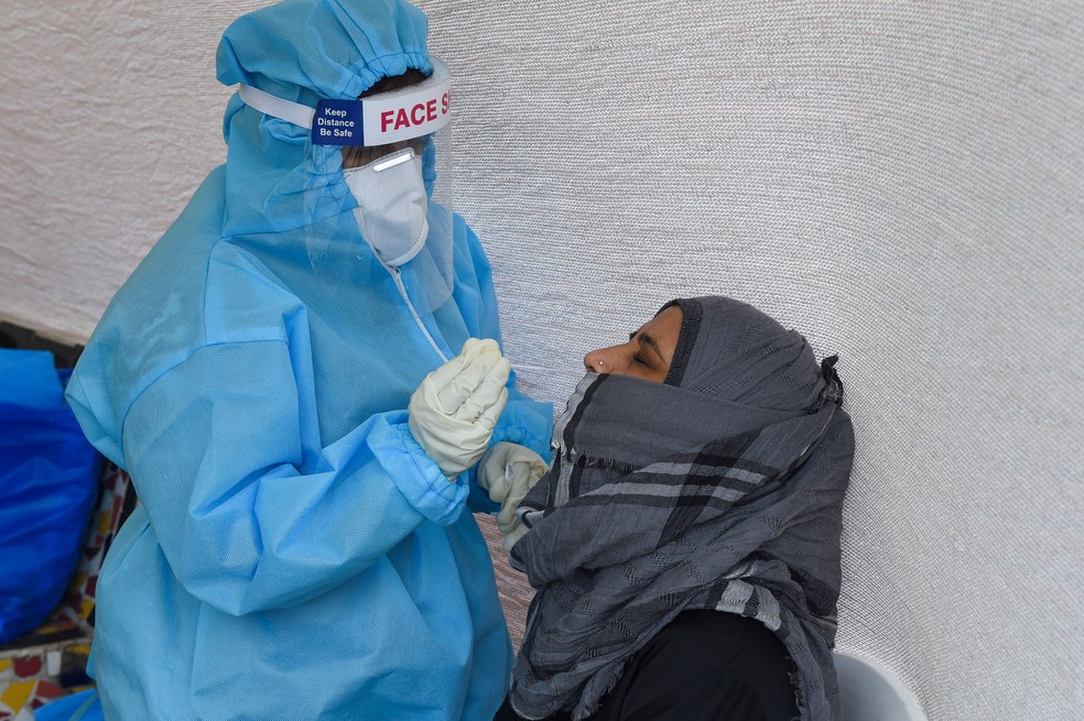 Mulher passa por coleta de material para exame de Covid-19 em Ahmedabad, na Índia, nesta segunda-feira (14)  — Foto: Sam Panthaky / AFP