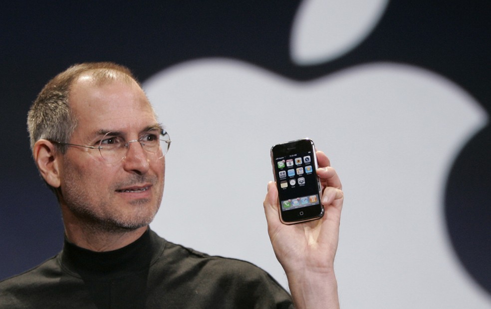 Jobs segura um iPhone durante o evento de lançamento da primeira versão do aparelho, em janeiro de 2007 — Foto: Paul Sakuma/Associated Press
