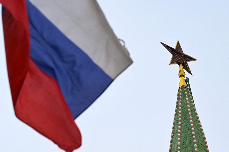 Bandeira da Rússia tremula ao lado de estrela no Kremlin.