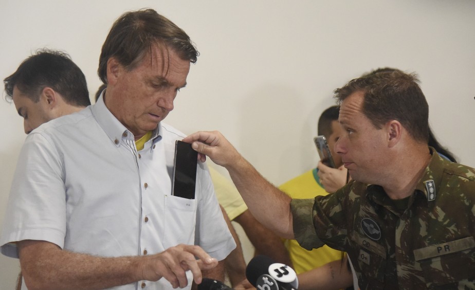 Mauro Cid tira celular do bolso de Jair Bolsonaro no Aeroporto de Guarulhos, em 2022