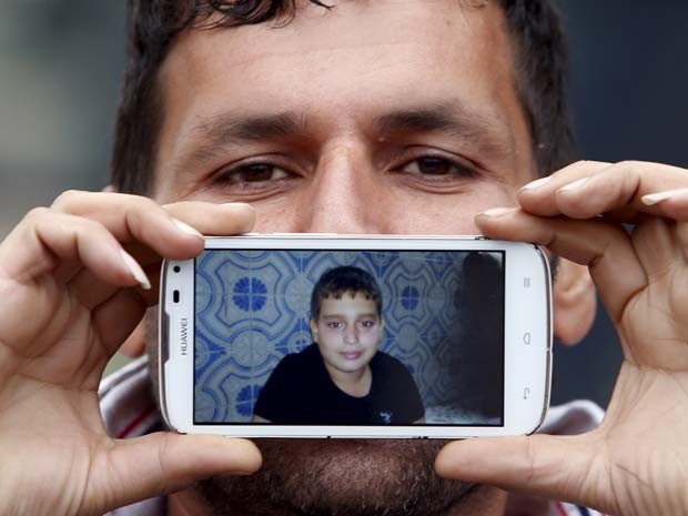 Said, de Terã, no Irã, mostra a foto do filho Hossein ao esperar na fronteira (Foto: REUTERS/Srdjan Zivulovic)