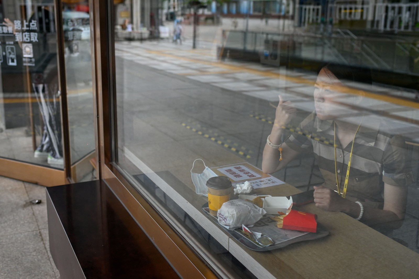 Mulher come um lanche em loja de fast food, em Pequim, depois que o governo aliviou algumas restrições impostas pelo surto de  Covid-19. — Foto: WANG Zhao / AFP