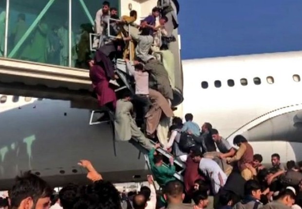 Civis afegãos tentam desesperadamente embarcar em avião no aeroporto de Cabul (Foto: BBC)