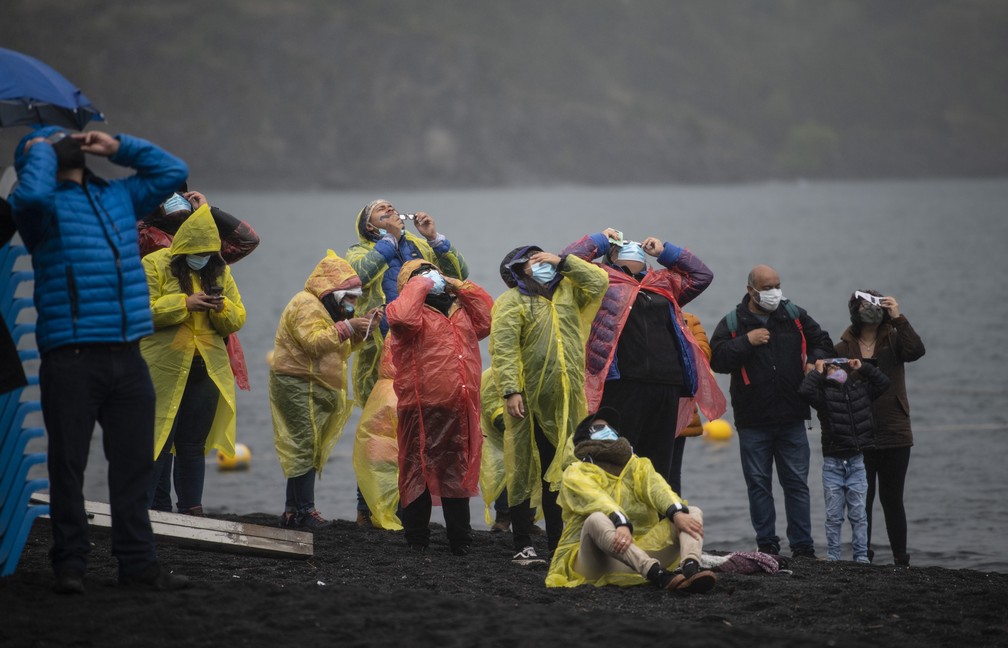 Pessoas assistem ao eclipse solar total nas margens do lago Villarrica em Pucon, no sul do Chile, nesta segunda-feira (14).  — Foto: Martin Bernetti/AFP