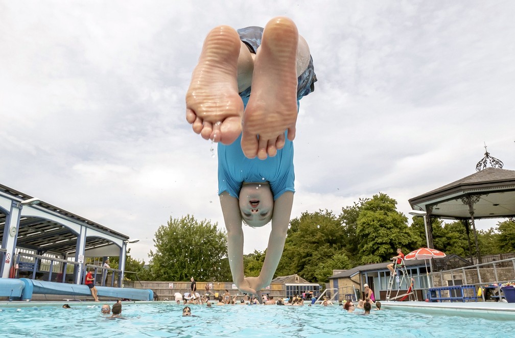 Criança mergulha em uma piscina pública de Sheffield, cidade no centro-norte da Inglaterra, neste domingo (17). — Foto: Danny Lawson/PA via AP