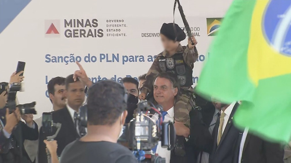 Bolsonaro com criança fardada sobre os ombros (Foto: Reprodução TV Globo)