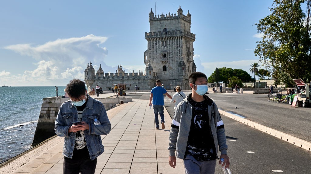 Turistas circulam usando máscara próximo à Torre de Belém, à beira do Rio Tejo, em Lisboa (Foto: Getty Images)
