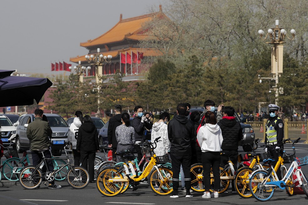 Um grupo de pessoas faz uma pausa perto da Praça da Paz Celestial, em Pequim, para em homenagem aos mortos pelo novo coronavírus — Foto: Andy Wong / AP Photo