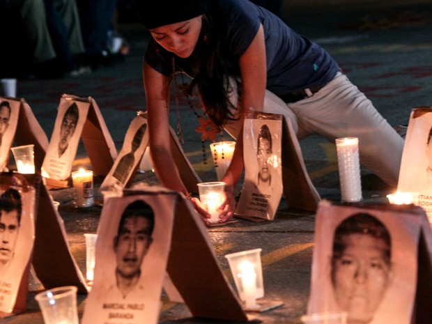 Uma menina acende velas durante uma vigília para os 43 estudantes desaparecidos em Chilpancingo, no México. Os alunos estão desaparecidos desde 26 de setembro quando foram atacados a tiros por policiais e entregues ao cartel de criminosos Guerreros Unidos (Foto: Pablo Spencer/AFP)