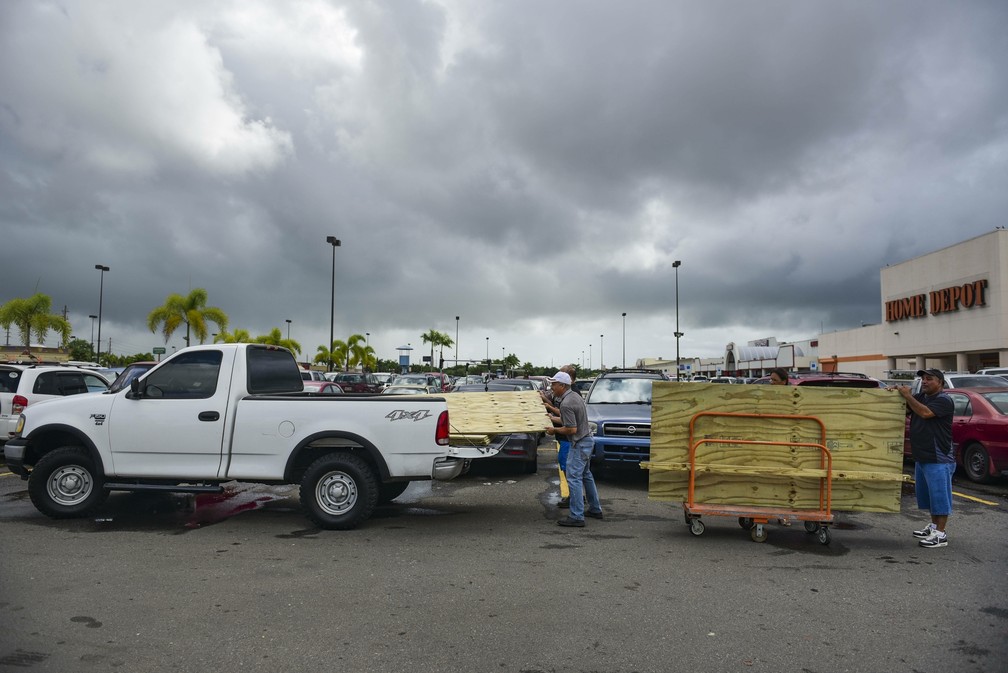 Homens carregam tábuas de madeira para proteger janelas antes da passagem do furacão Irma em Carolina, Porto Rico  (Foto: AP Foto/Carlos Giusti)