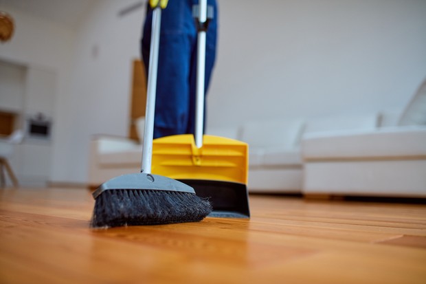 Young cleaner sweep the floor in living room. Cleaning service (Foto: Getty Images/iStockphoto)