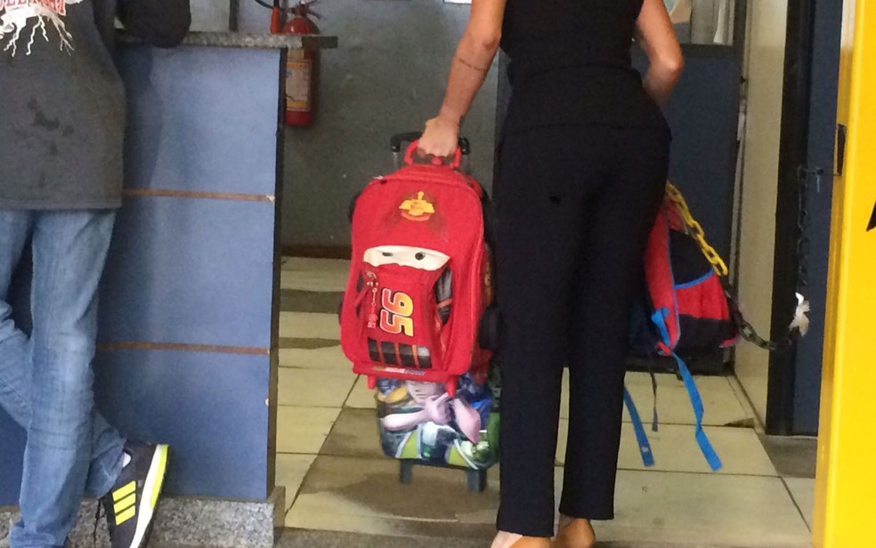 Agente leva mochilas das crianças que estavam em van roubada por criminosos (Foto: Bruno Albernaz / G1)
