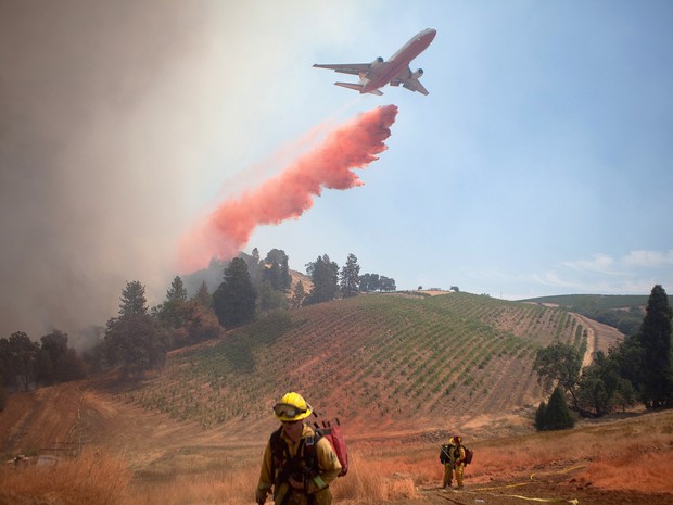 Avião sobrevoa a região do incêndio e lança produto para ajudar no combate ao fogo nos Estados Unidos (Foto: Max Whittaker/Reuters)