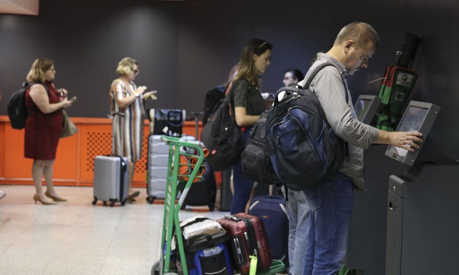 Passageiros com bagagens fazem check in em aeroporto