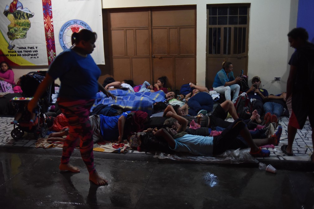 Imigrantes hondurenhos integrantes de caravana que segue para os Estados Unidos descansam no chão da igreja em Tecún Umán, na fronteira com o México, na noite de quinta-feira (18)  — Foto: Johan Ordonez / AFP
