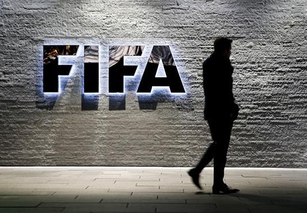 Jornalista caminha diante do logotipo da FIFA na sede da instituição na Suíça (Foto: Arnd Wiegmann/REUTERS)