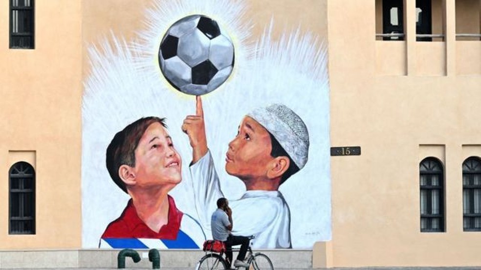 Um mural mostrando duas crianças e uma bola de futebol no Catar — Foto: GETTY IMAGES/via BBC