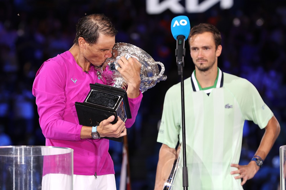 Rafael Nadal beija taça do Australian Open observado por Daniil Medvedev — Foto: Getty Images