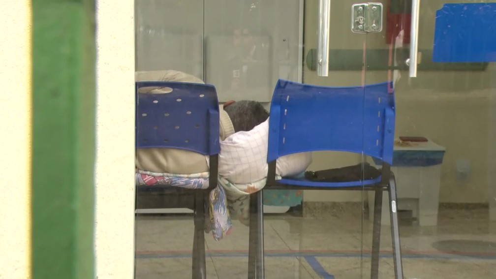 Homem deitado em cadeiras de plástico por não ter leitos disponíveis em Bonsucesso — Foto: Felipe Azevedo/ TV Globo
