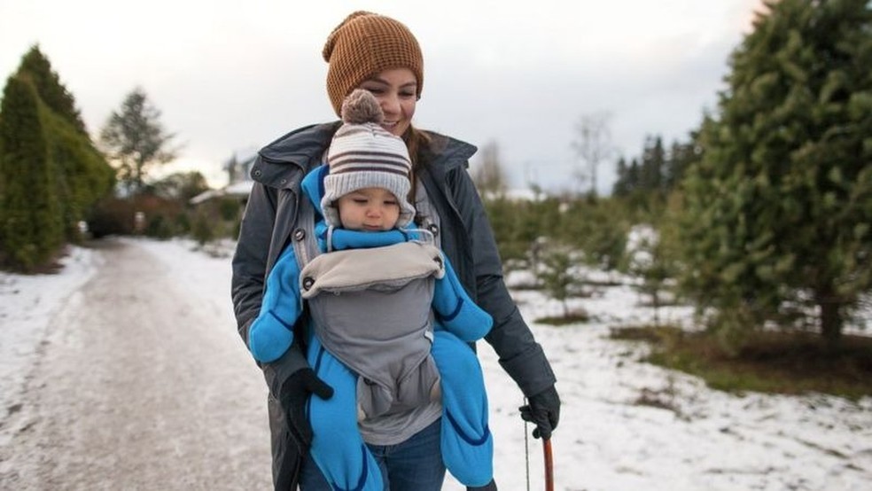 Mulher carrega bebê em dia frio — Foto: Getty Images/BBC
