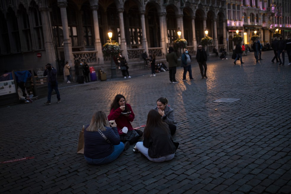 Estudantes espanhóis comem waffles na Grand Place na sexta-feira (23), no centro de Bruxelas, antes do toque de recolher — Foto: Francisco Seco/AP
