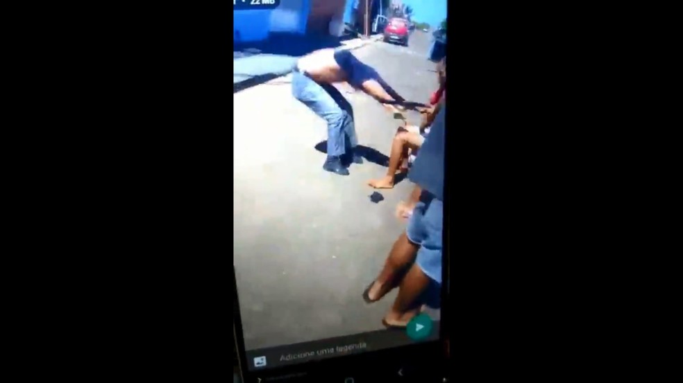 Policial é segurado pela camiseta por moradora após ser agredido — Foto: Reprodução