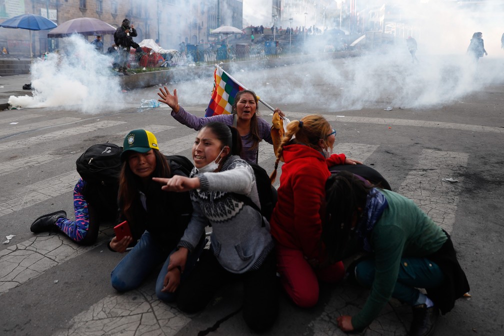 15 de novembro - Apoiadores do ex-presidente Evo Morales se protegem de bombas de gás disparadas pela polícia durante manfestação em La Paz, na Bolívia. Dias antes, Morales havia renunciado à presidência da Bolívia após uma escalada nas tensões no país  — Foto: Natacha Pisarenko/AP