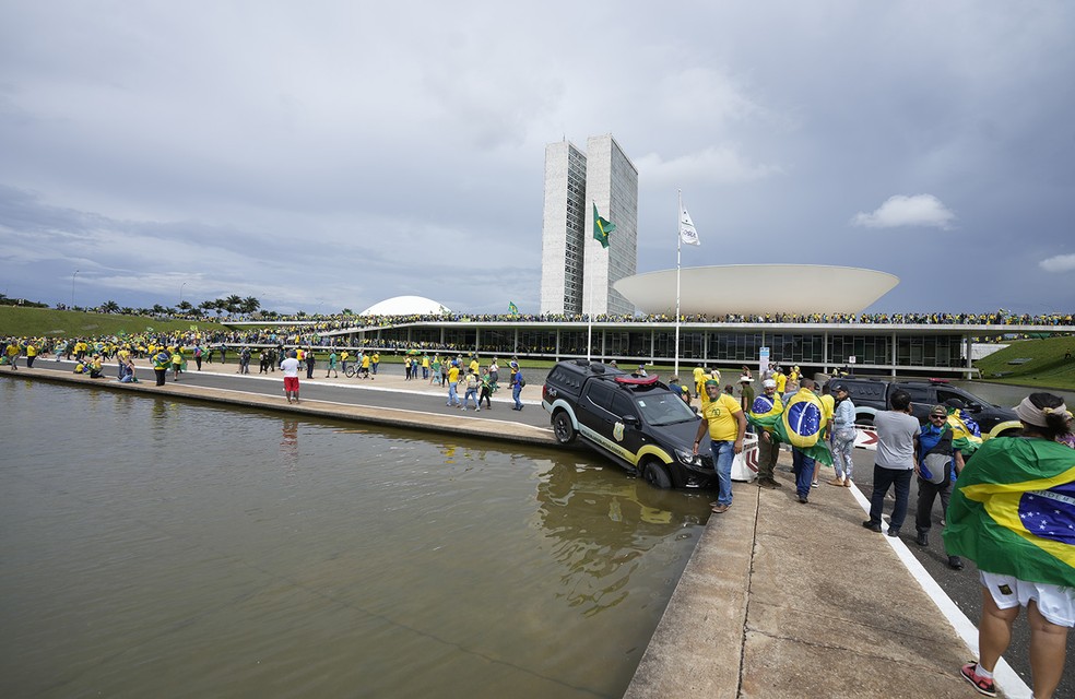 Viatura policial foi empurrada por vândalos para dentro de um espelho d'água diante do Congresso — Foto: Eraldo Peres/AP