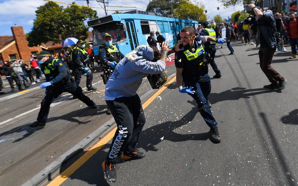 Policiais disparam spray de pimenta durante confronto com manifestantes contra o confinamento em Melbourne, na Austrália, no sábado (18) — Foto: James Ross/AAP Image via AP