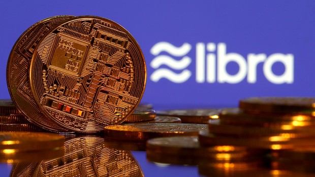 Representações de moedas virtuais em frente ao logo da moeda Libra (Facebook) (Foto: REUTERS/Dado Ruvic)