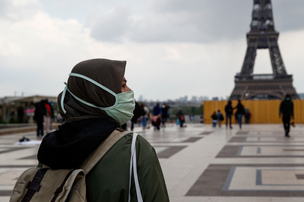 Uma mulher, usando um hijab e uma máscara protetora, caminha na praça Trocadero, perto da Torre Eiffel, em Paris, França, 2 de maio de 2021 — Foto: REUTERS/Gonzalo Fuentes