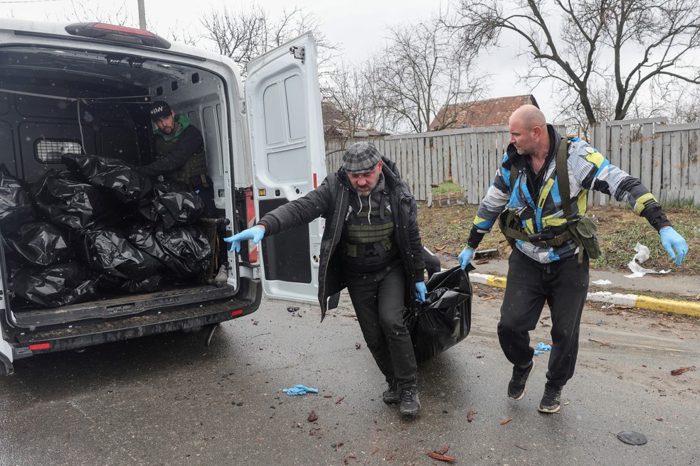 Guerra na Ucrânia - voluntários recolhem corpos de civis mortos por soldados russos em Bucha, segundo moradores.  — Foto: REUTERS/Stringer
