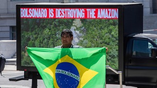 Toya Manchineri durante protesto em Los Angeles, em que segura uma bandeira com os dizeres "Fora, Bolsonaro" — Foto: APU GOMES / AFP