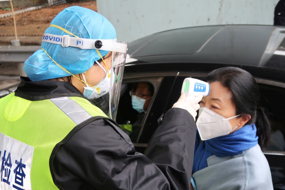 Coronavírus: oficial com máscara protetora verifica temperatura de passageiro em um pedágio entre Xianning e Wuhan, na China, em meio às restrições de circulação de pessoas, que tenta frear a expansão da doença. — Foto: Martin Pollard/Reuters.