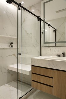 O escritório Beta Arquitetura elaborou um banheiro com aspecto mais minimalista, por meio do uso de metais escuros e revestimentos claros. Marcenaria assinada pela Lacca Móveis